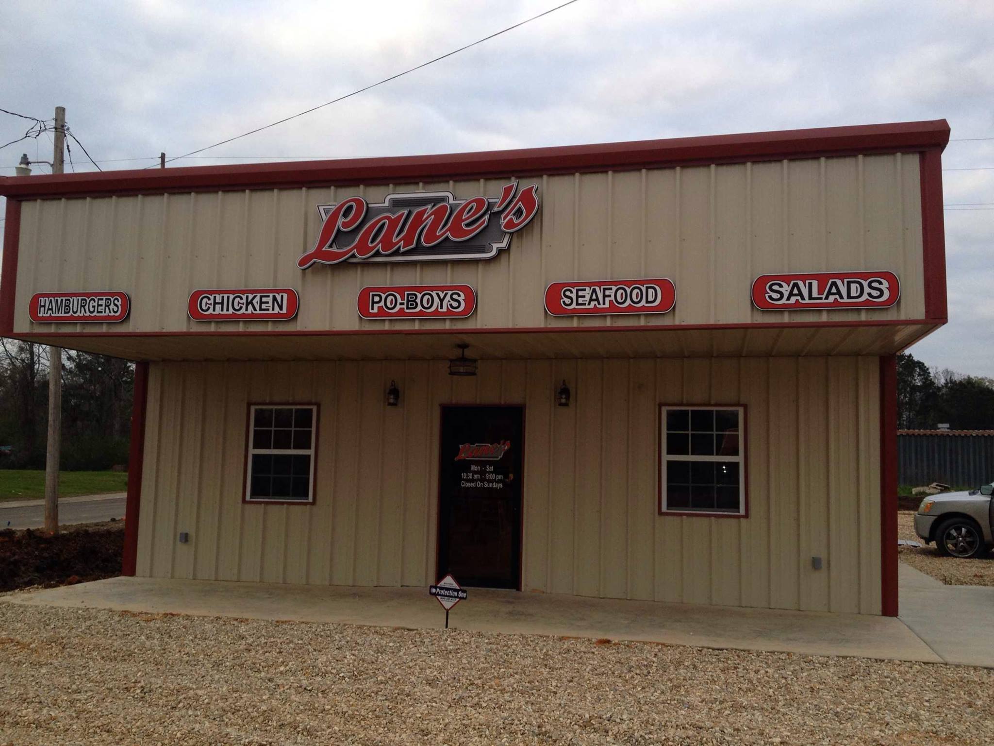 Lane's red-roofed restaurant building with signs for hamburgers, chicken, po-boys, seafood and salads