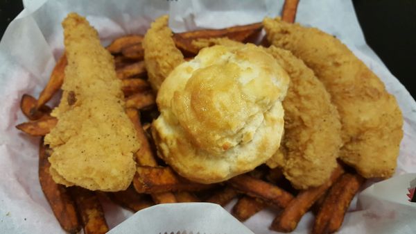 Fried chicken tenders, fries and a biscuit in a basket