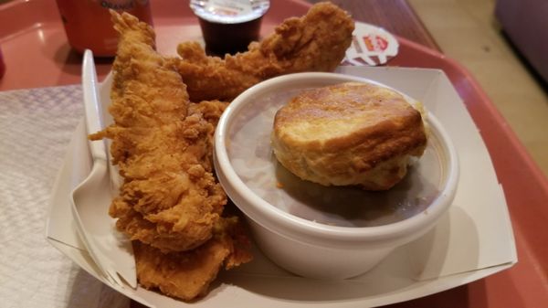 Tray of fried chicken strips with a biscuit and a drink